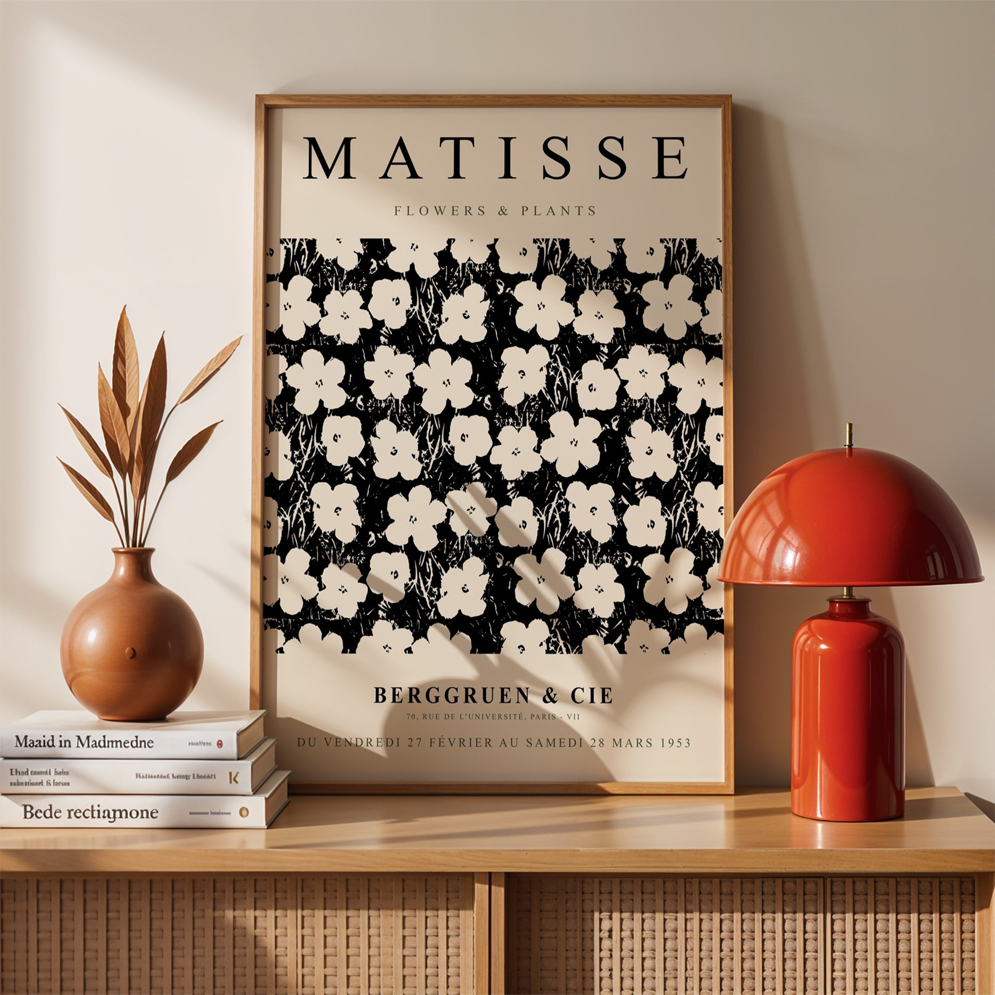 framed artwork featuring black and white floral and plant illustrations in the style of Matisse displayed on a light wall with decorative elements around it