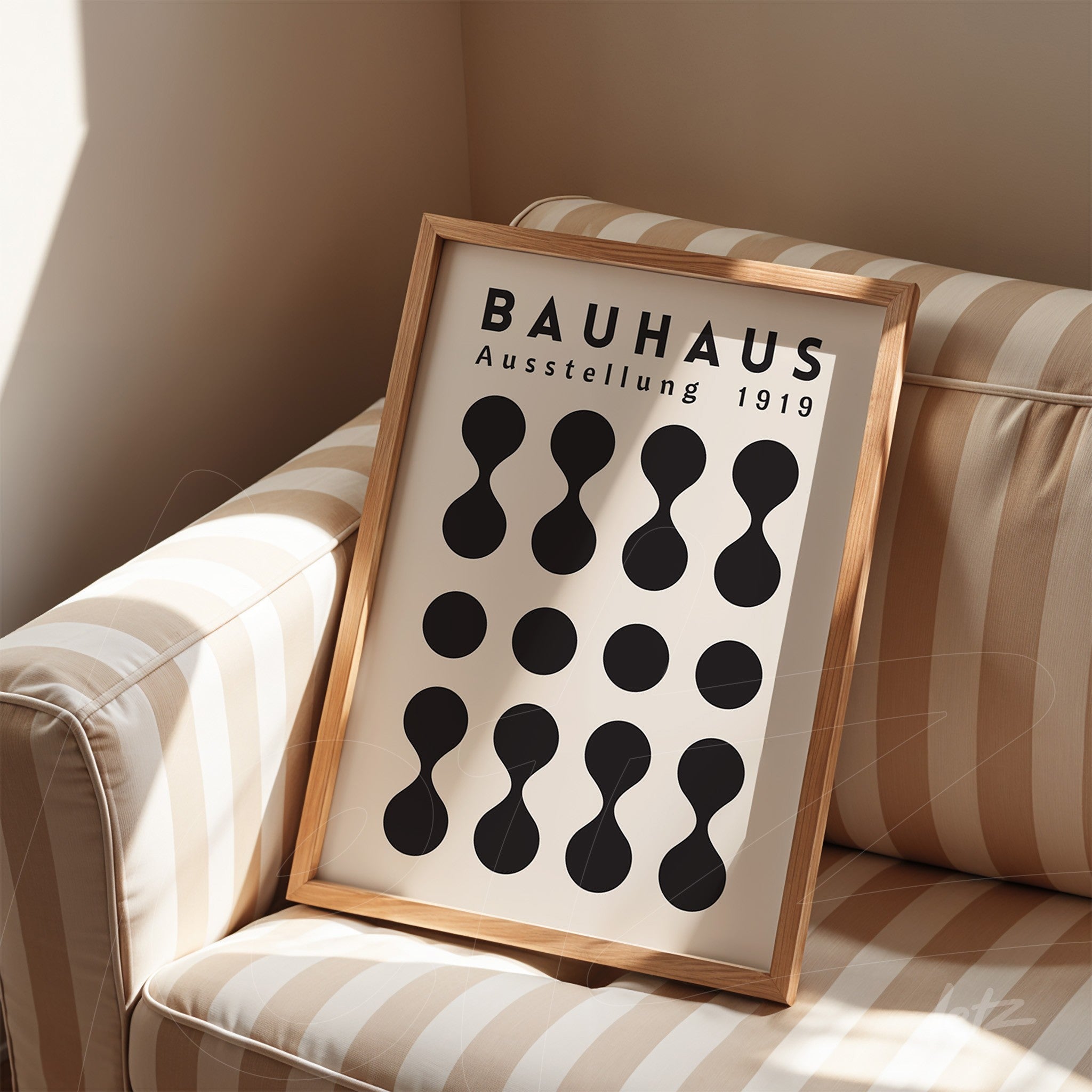 poster print featuring bauhaus design in light wood frame placed on a striped couch