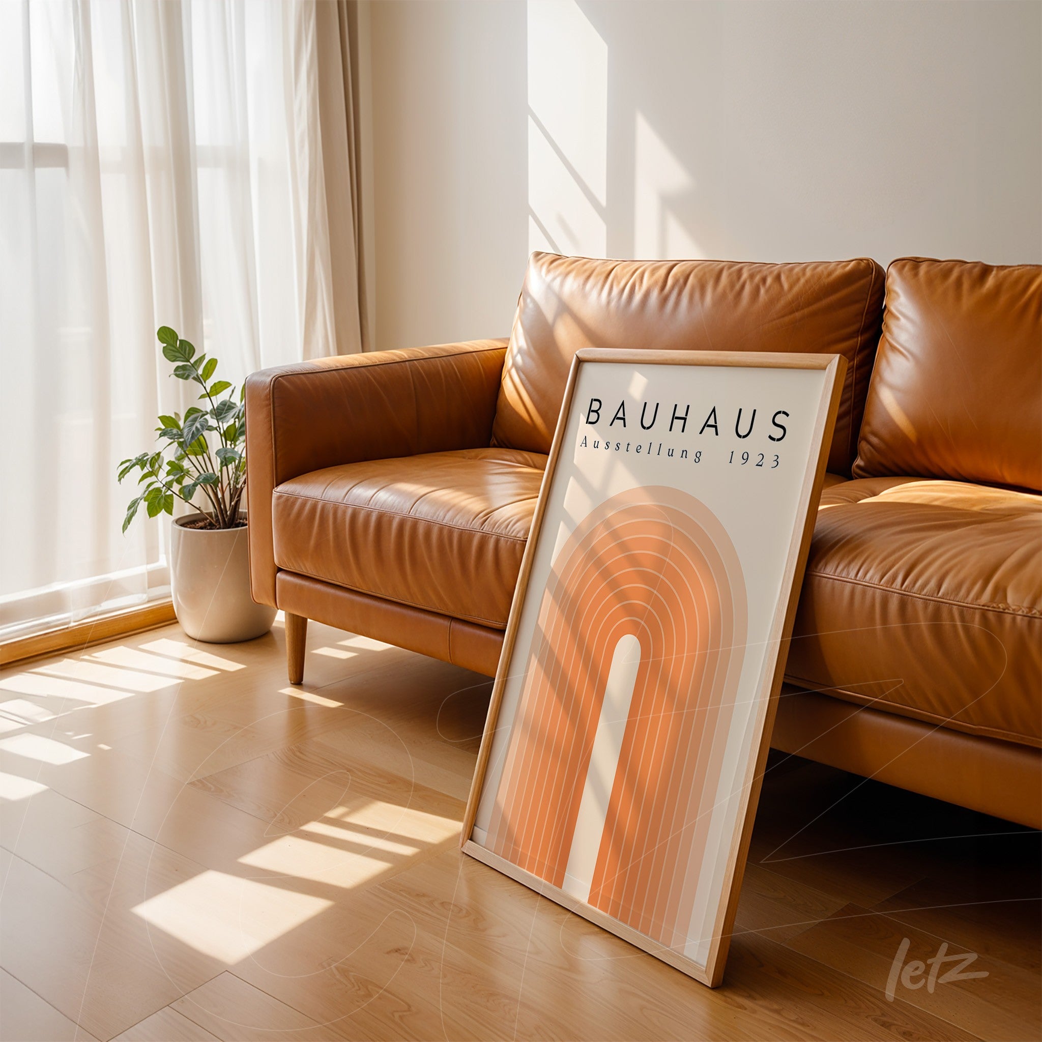 poster print with bauhaus-style geometric design in orange hues, leaning on leather sofa in sunlit room
