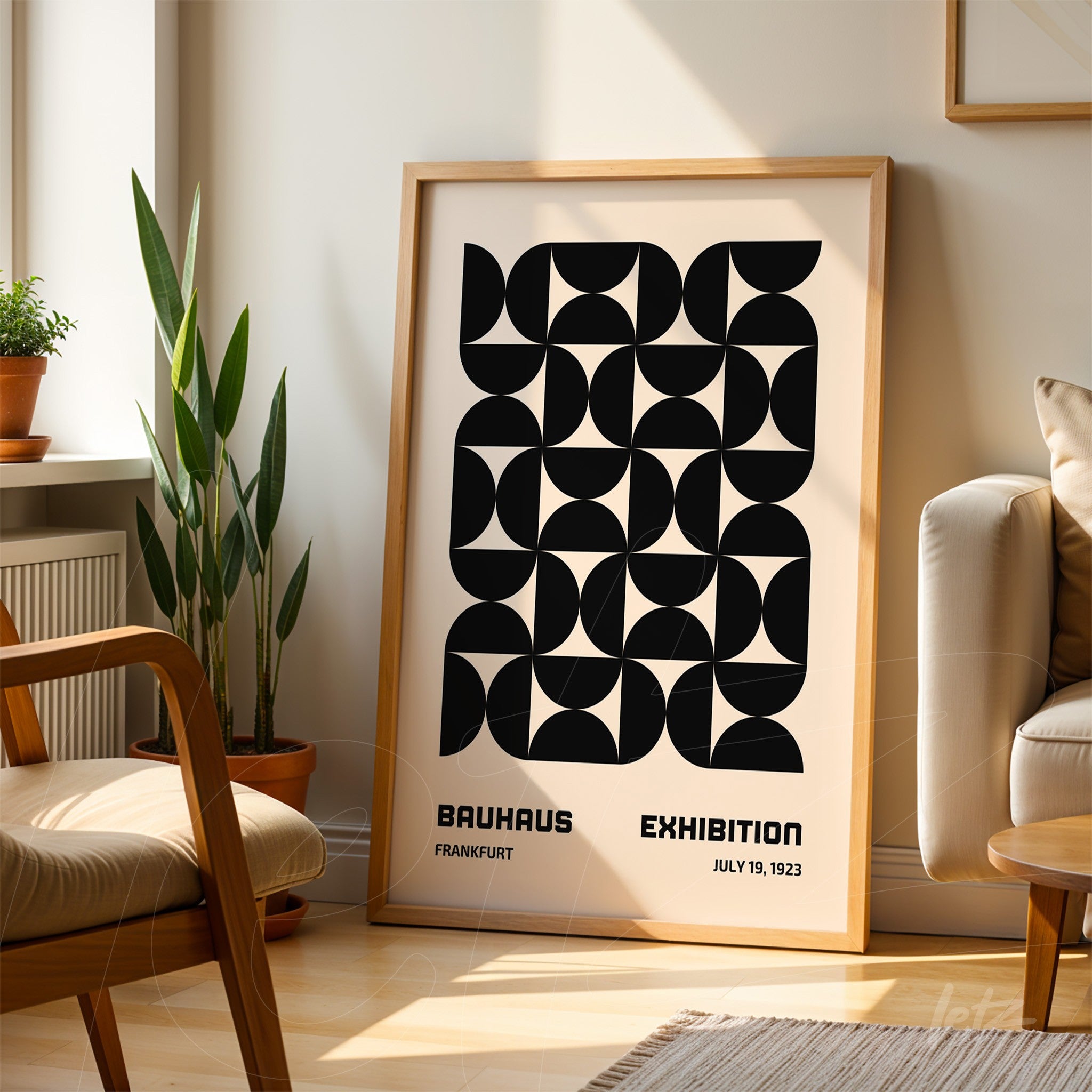 printed poster featuring geometric bauhaus style art in a light wooden frame leaning against a white wall next to a plant