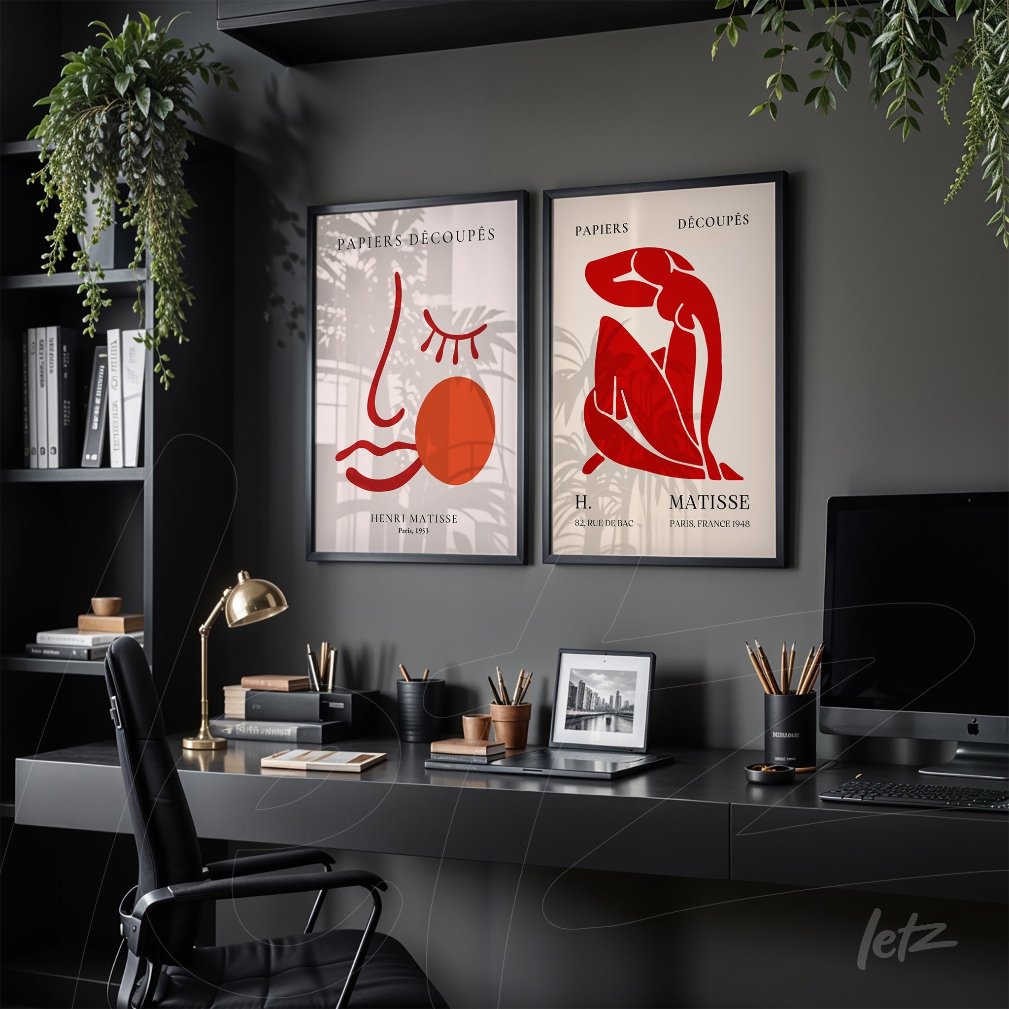 composition with two framed decorative artworks in black frames, one featuring an abstract line drawing of a face with a red circle, and the other depicting a minimalist female figure, both displayed against a dark wall in an office setting