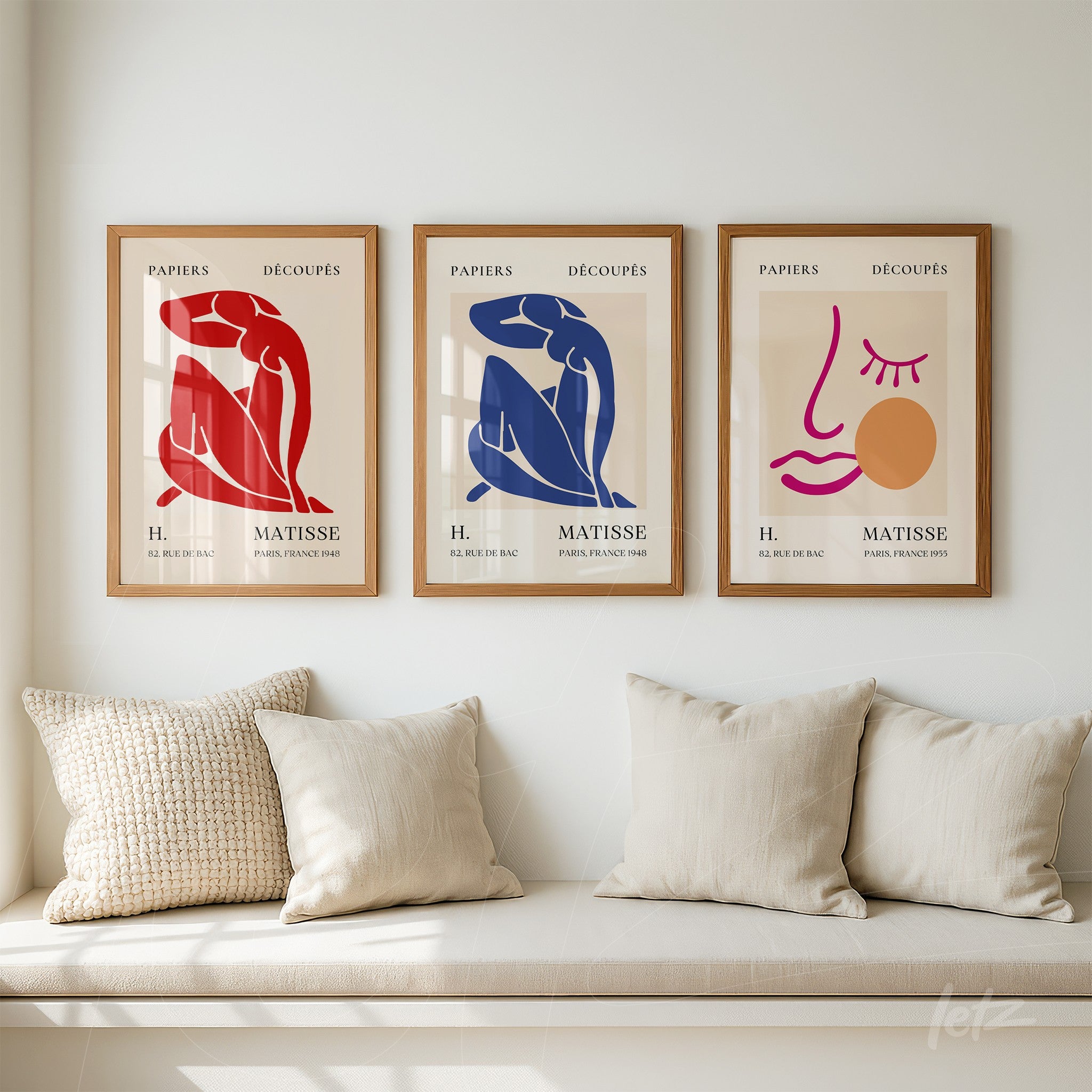 trio of framed wall art in minimalist style with light wood frames featuring vibrant human figures arranged on a beige wall above a sofa with light cushions