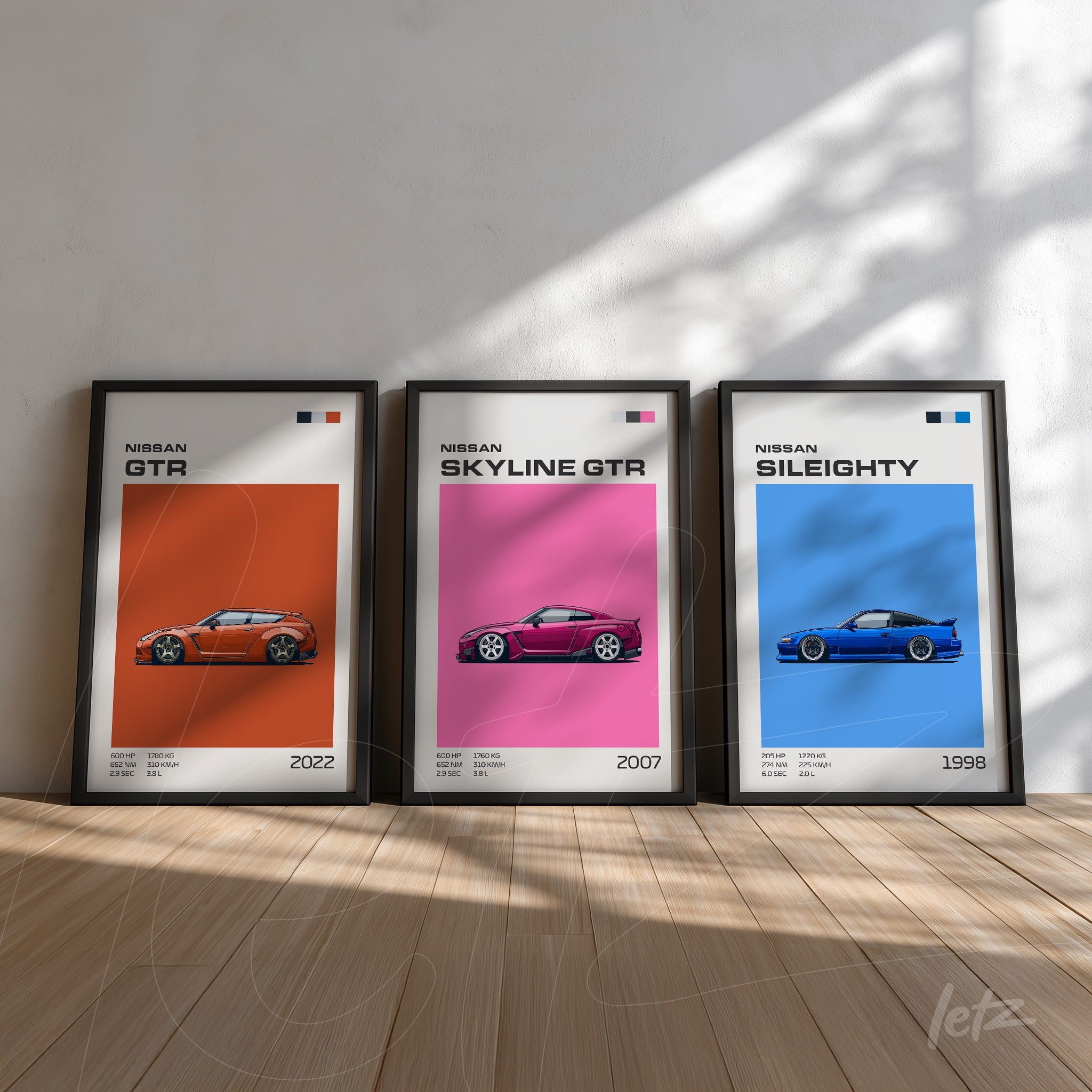collection of framed art featuring sports cars Nissan GTR, Skyline GTR, and Sil80 with black frames on light wooden background
