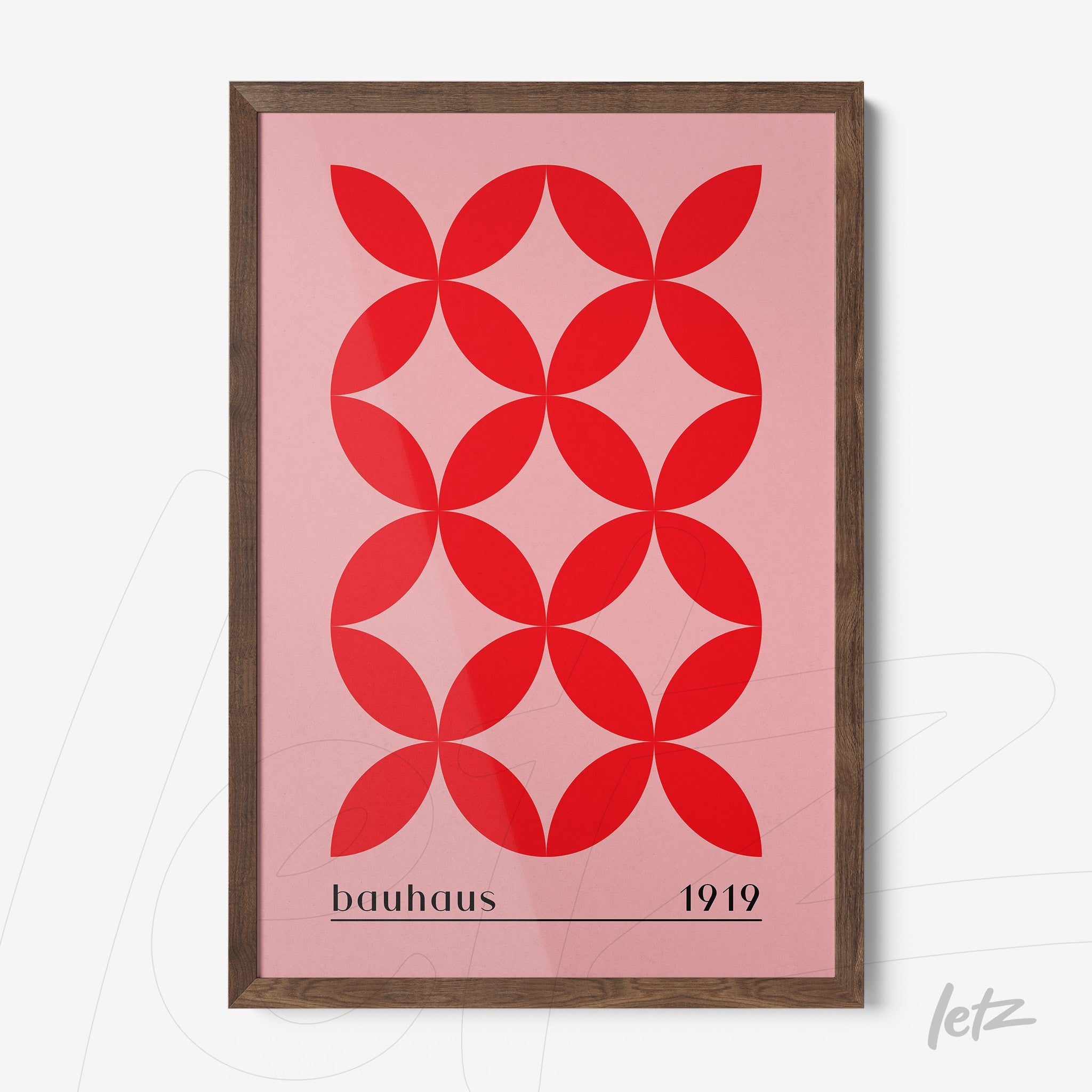 framed geometric illustration in shades of red on pink background with dark wooden frame, featuring the text bauhaus 1919