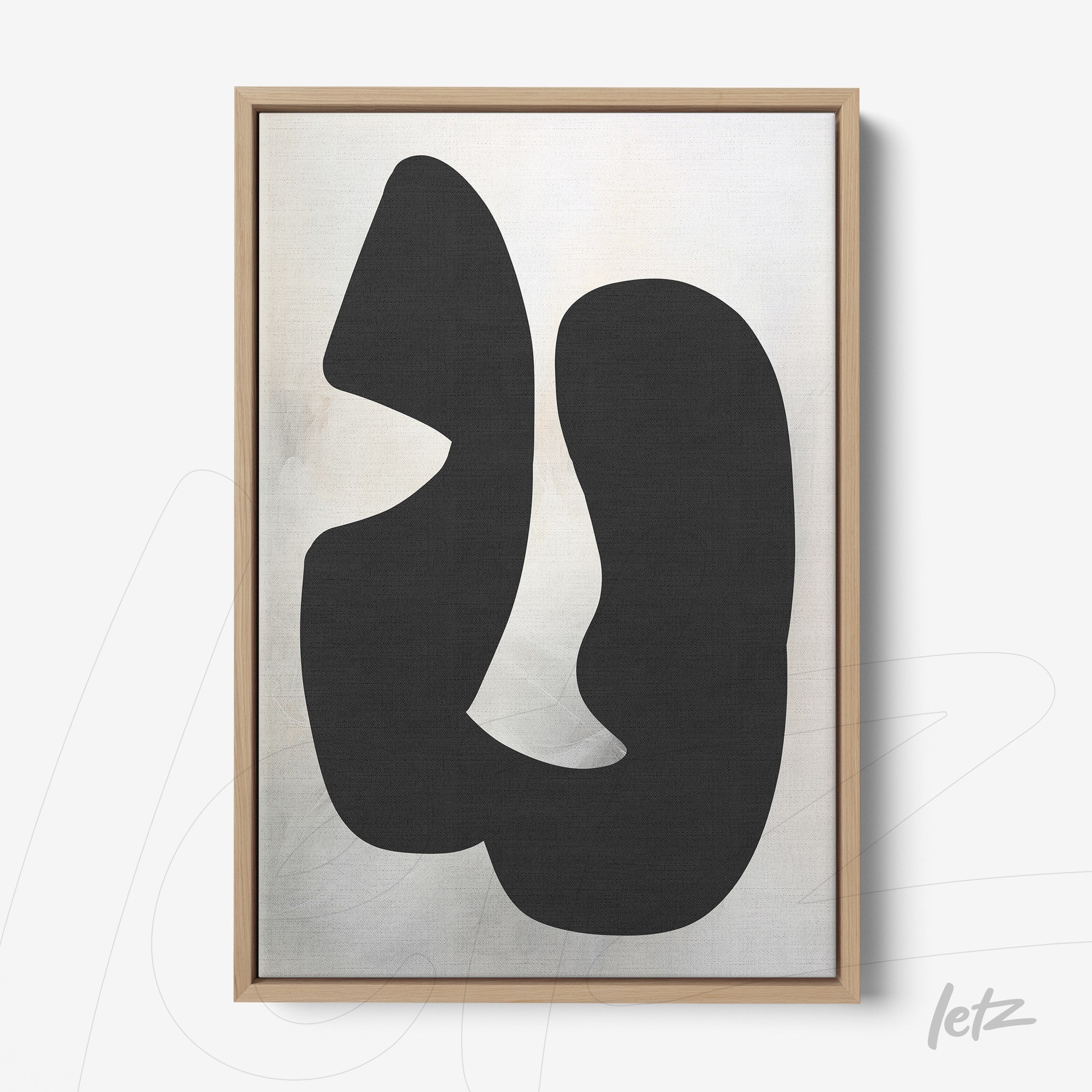 framed wall art featuring an abstract black composition on a light background with a light wood frame