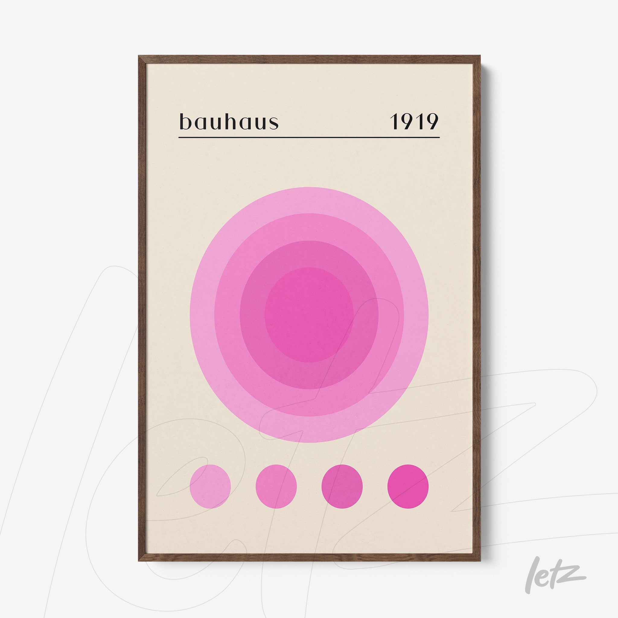 framed wall art with concentric circles in shades of pink and text bauhaus 1919 in wooden frame