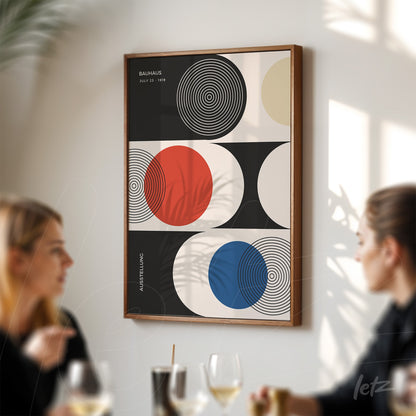 poster featuring geometric art of the Bauhaus movement in a wooden frame displayed on a white wall