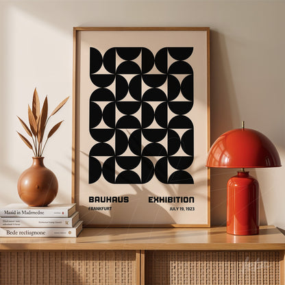 poster print featuring abstract geometric design in bauhaus style, displayed in a simple frame on a wooden sideboard next to a red lamp