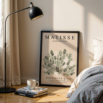 framed modern artwork by matisse featuring green and white leaves leaning next to a lamp in a bright room