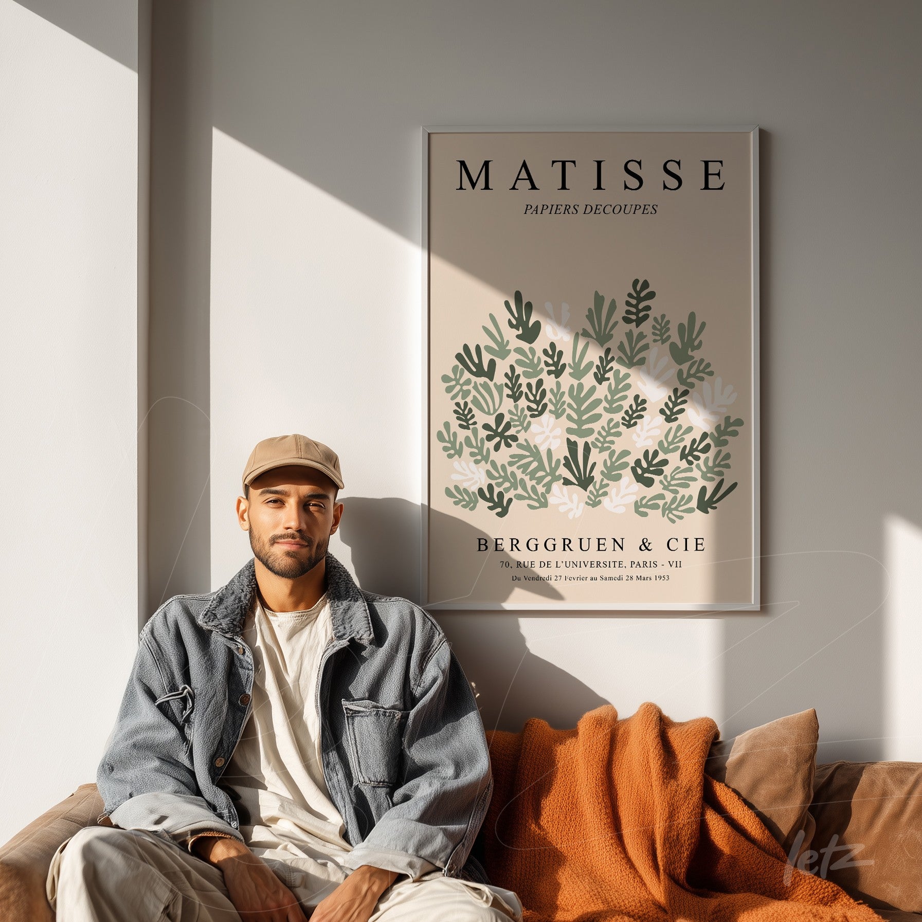 framed art print of Matisse's cut papers displayed on light wall next to a man sitting on a sofa