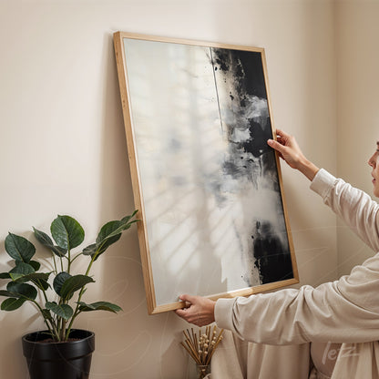 abstract framed wall art in light wood featuring a predominance of black and white, displayed against a light wall