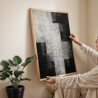 abstract black and white textured wall art with light wood frame displayed against a neutral wall