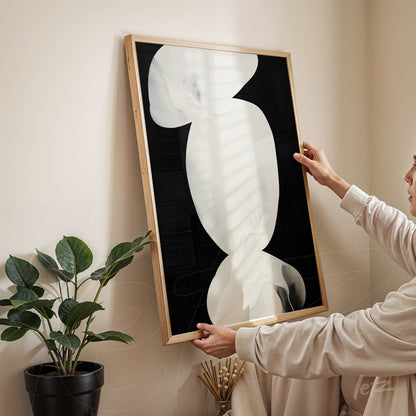 framed abstract art in white and black tones presented in a cozy setting