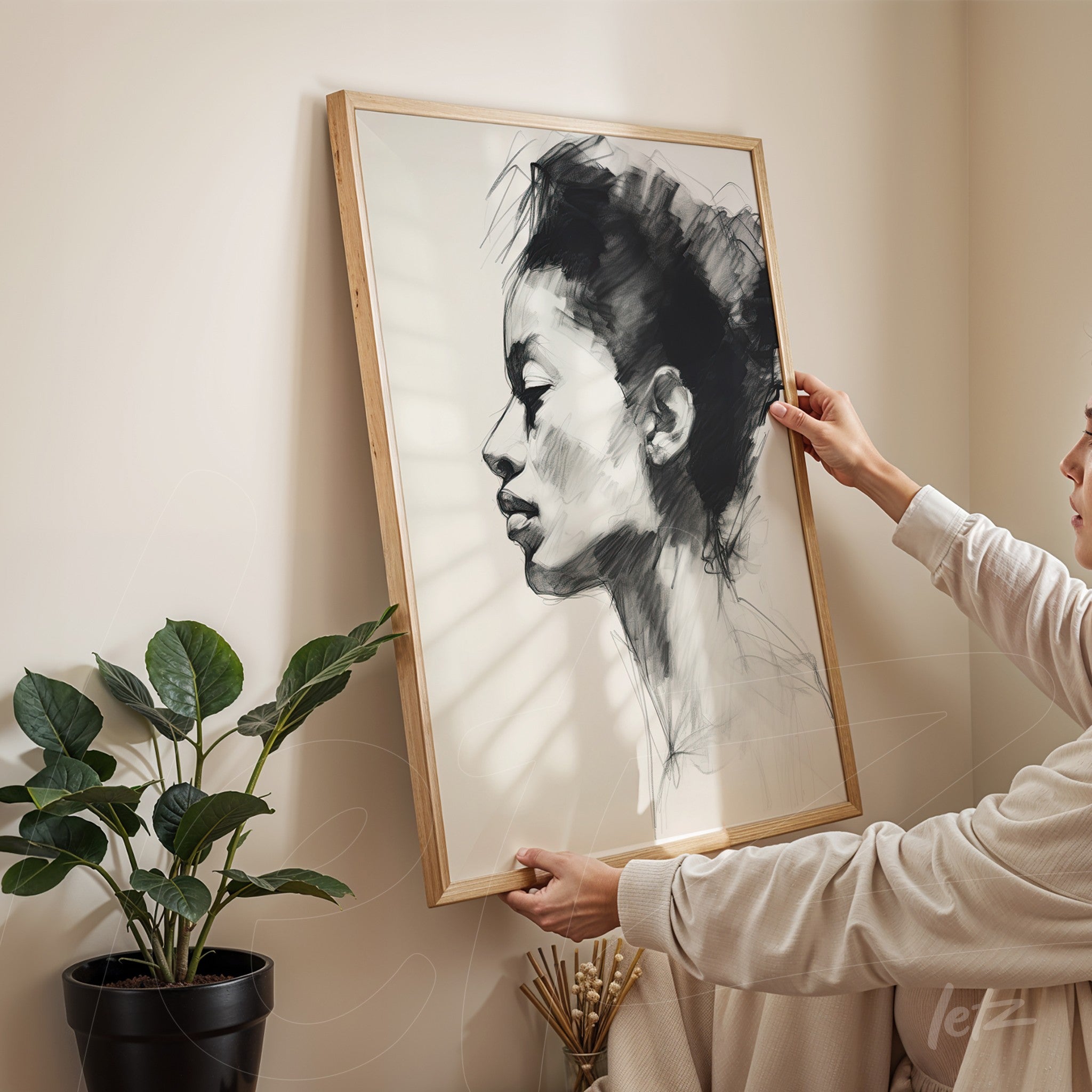 framed wall art of a female portrait in black and white, light wood frame displayed in a bright indoor setting