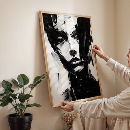 abstract artwork in black and white featuring a human figure in a natural wood frame displayed in a minimalist setting with a plant in the background