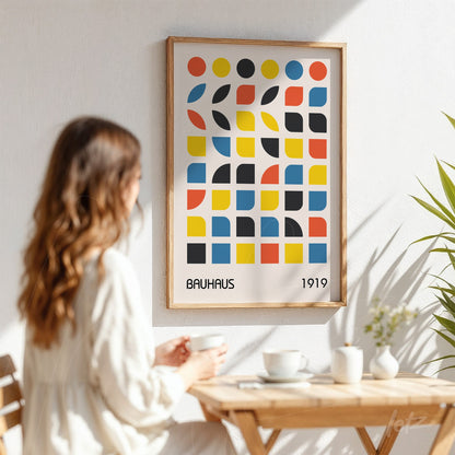 printed poster featuring geometric bauhaus style art in a light wood frame against a white wall