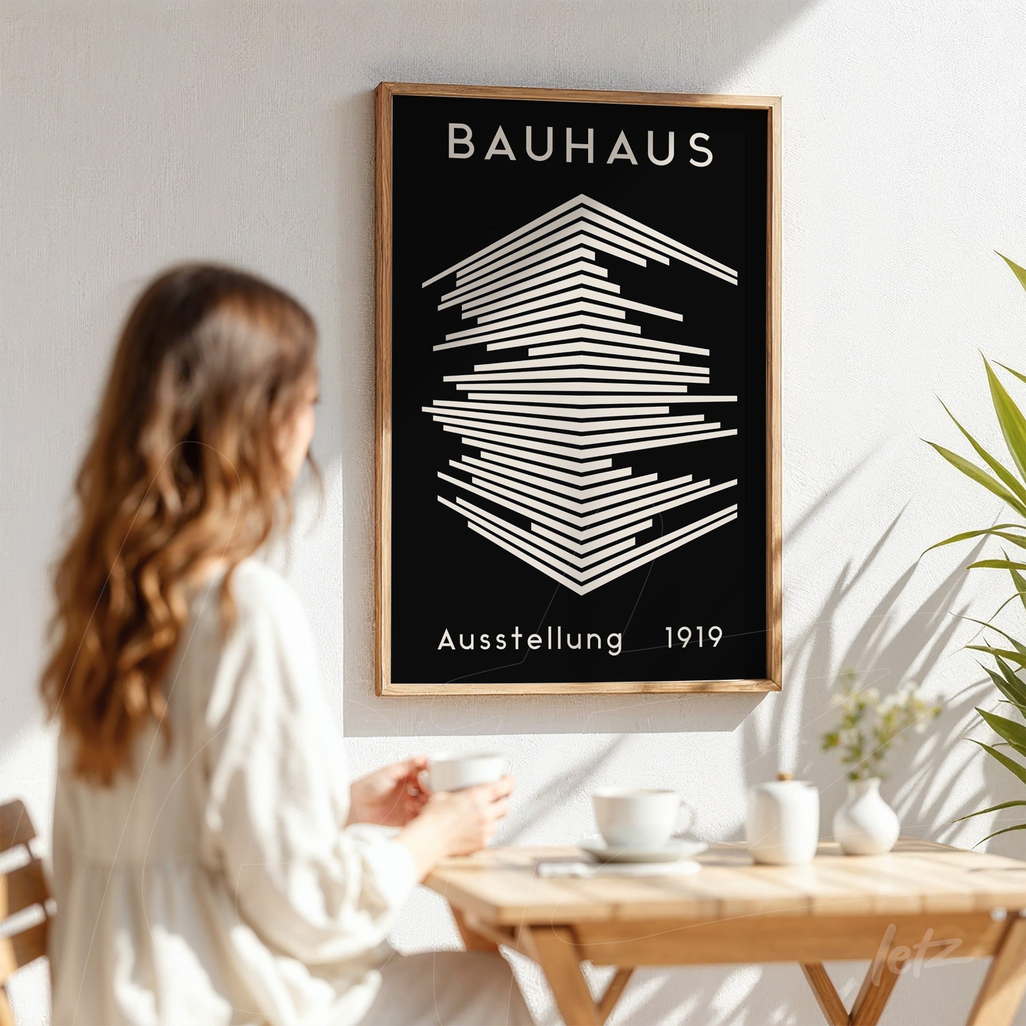 poster featuring geometric Bauhaus-inspired design from 1919 in a light wood frame displayed on a white wall