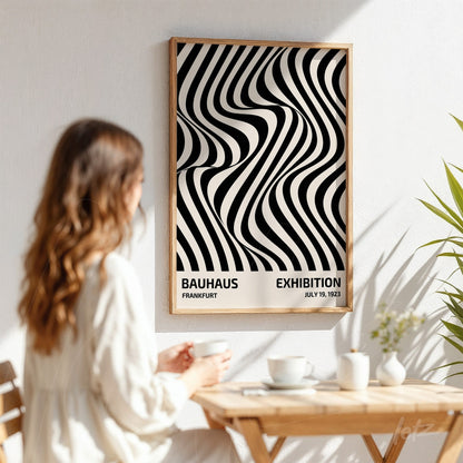 woman viewing abstract black and white poster with wavy pattern, light wood frame on white wall background