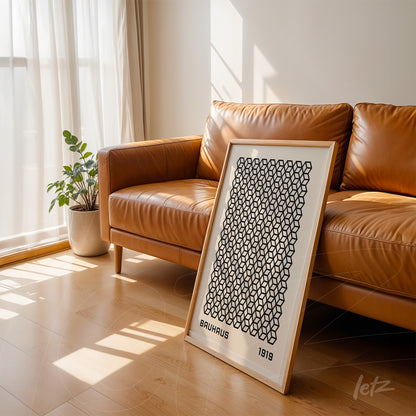 poster with geometric black pattern on white background leaning against brown leather sofa