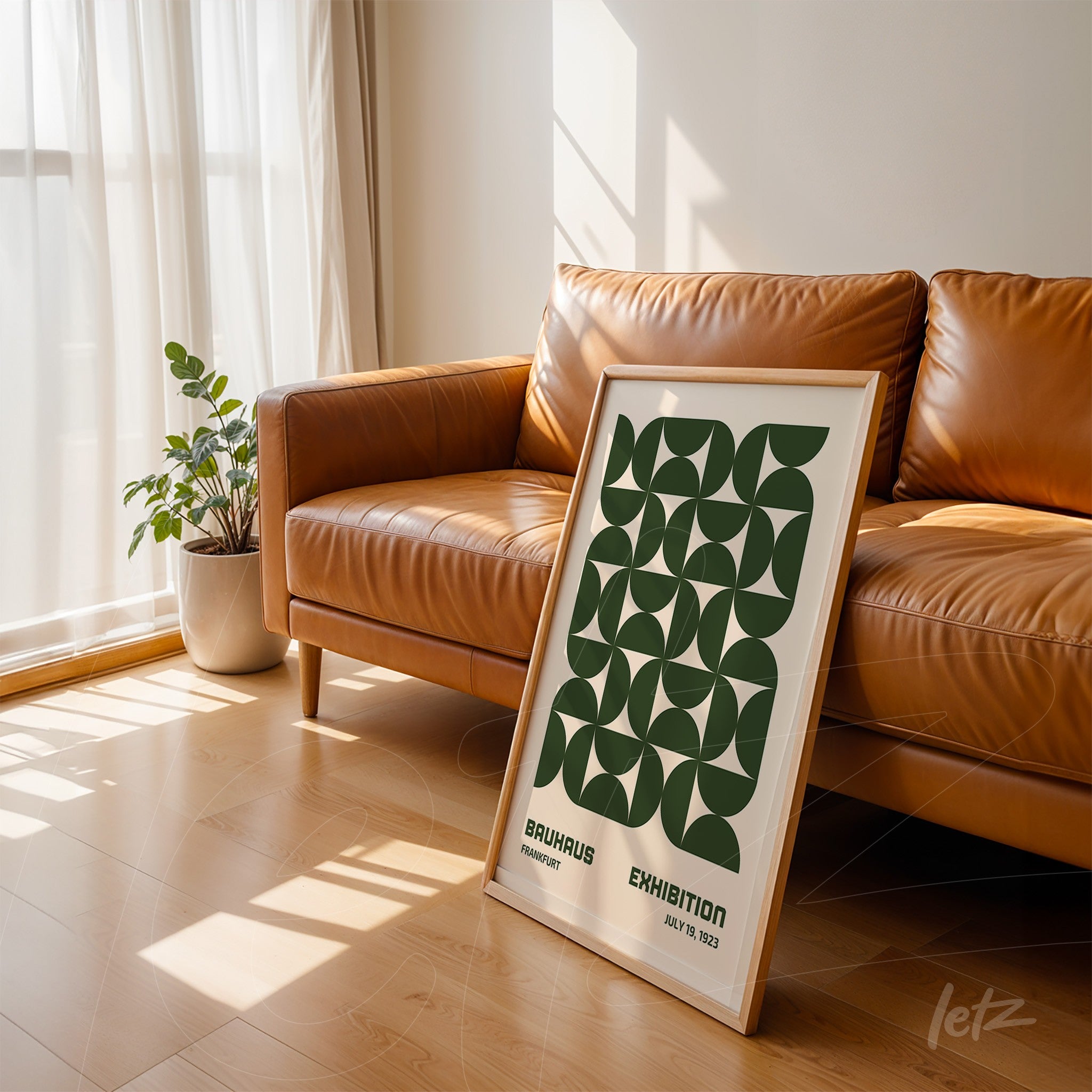 poster with green geometric design next to a brown sofa, resting on light wooden floor, framed with natural wood