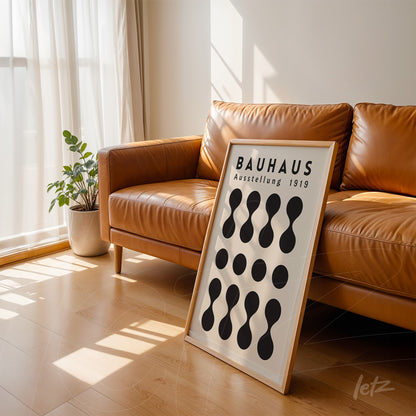black and white geometric Bauhaus inspired poster leaning against a brown leather sofa in a well-lit living room