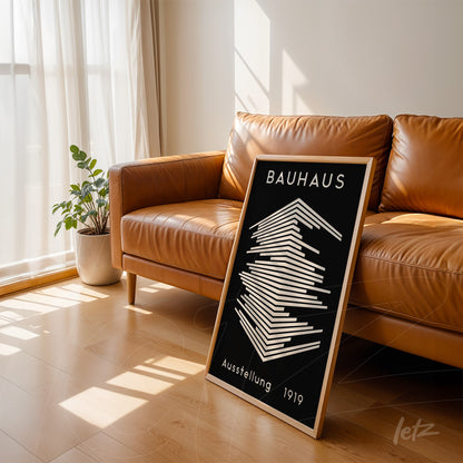 minimalist geometric Bauhaus style art in light wood frame leaning against a light brown leather sofa