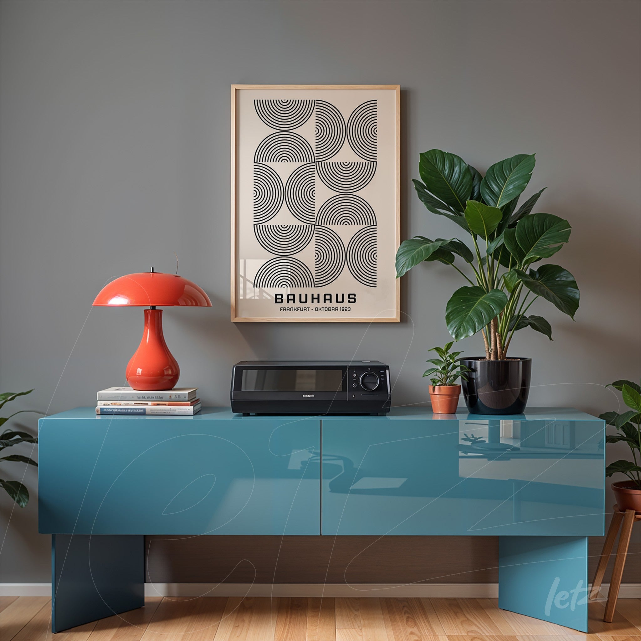 bauhaus style framed print hanging above a glossy blue sideboard with potted plants and retro red lamp