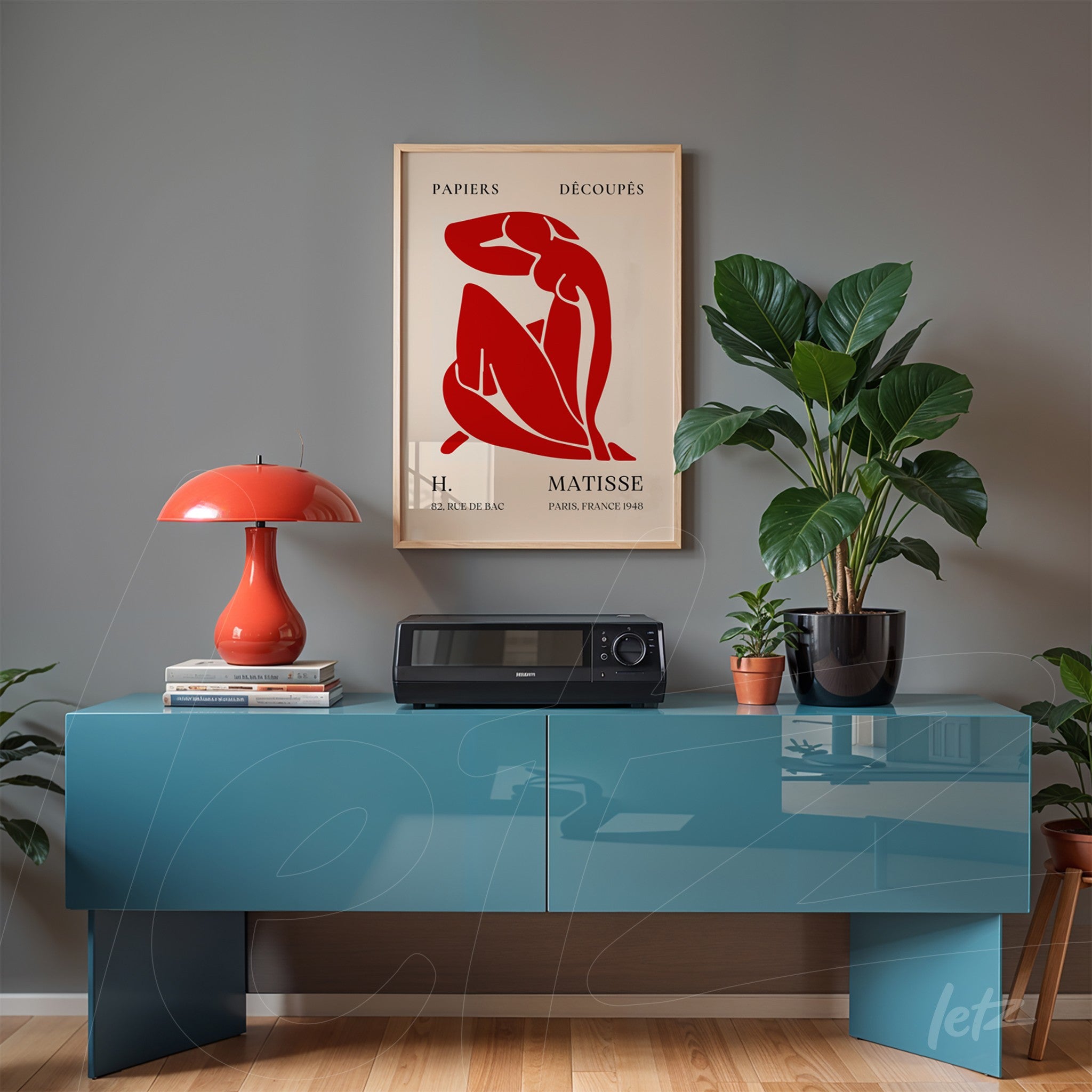 framed vintage style artwork by Matisse displayed above a blue table with greenery around