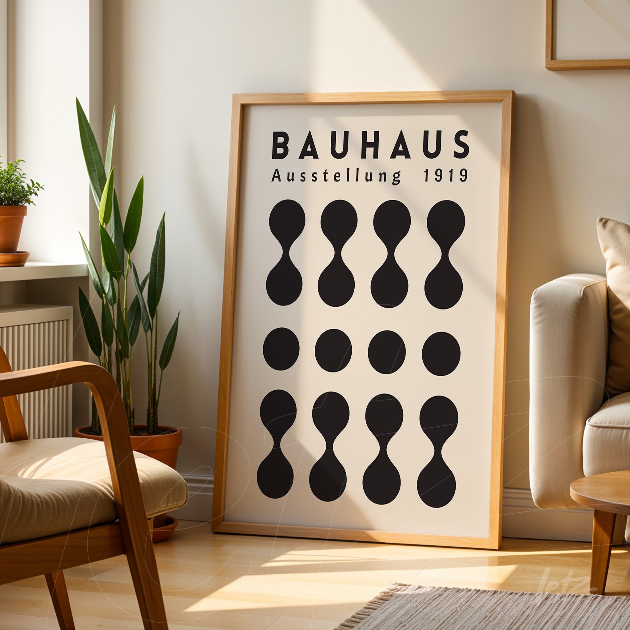 bauhaus style poster print with black geometric shapes in a light wood frame leaned against the wall next to a potted plant