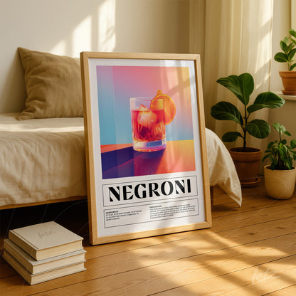 framed artwork featuring vibrant graphic of negroni cocktail with light wood frame in an interior setting with sofa and plants