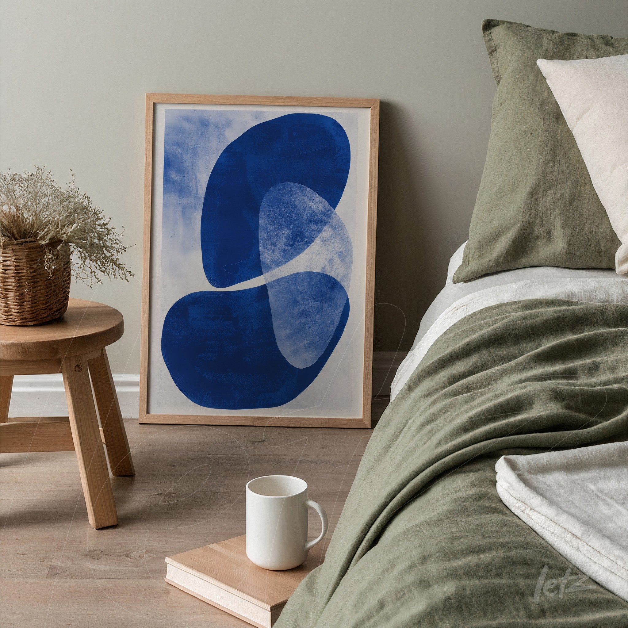 framed abstract wall art in blue and white next to a bed with neutral tone bedding