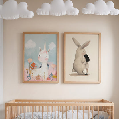 composition of two framed children's artworks with light wood frames, one featuring a unicorn amidst colorful flowers, and the other depicting a girl hugging a rabbit