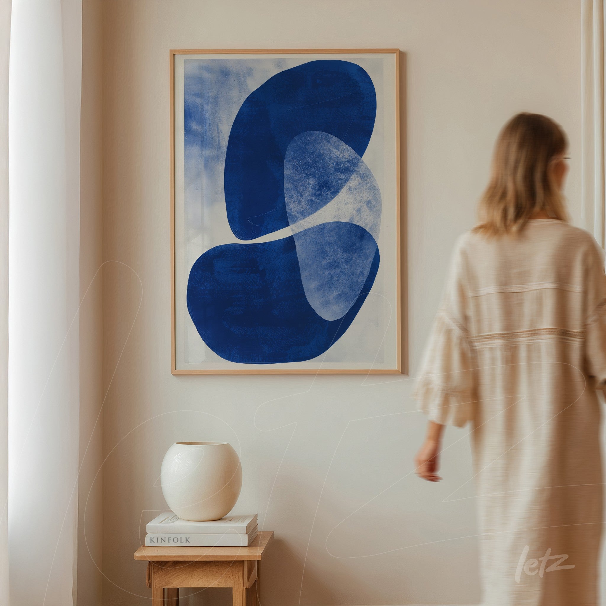 abstract art piece in navy blue framed in light wood on a neutral wall
