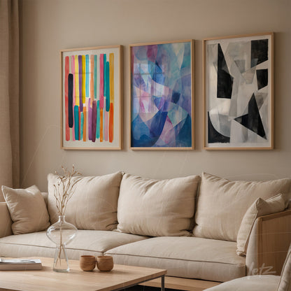 composition of three abstract framed artworks with light wood frames on beige wall, featuring the first with colorful stripes, the second in shades of blue, and the third in black and white