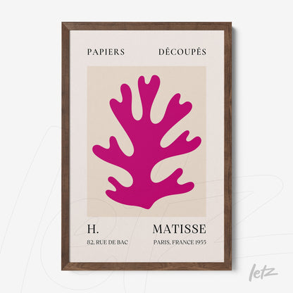 framed wall art with vibrant pink cut paper design against a neutral background in a light wood frame