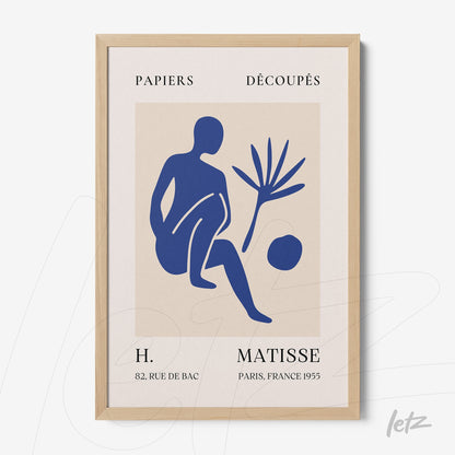 framed modern art print featuring paper cutouts of a blue human figure and a plant, light wood frame