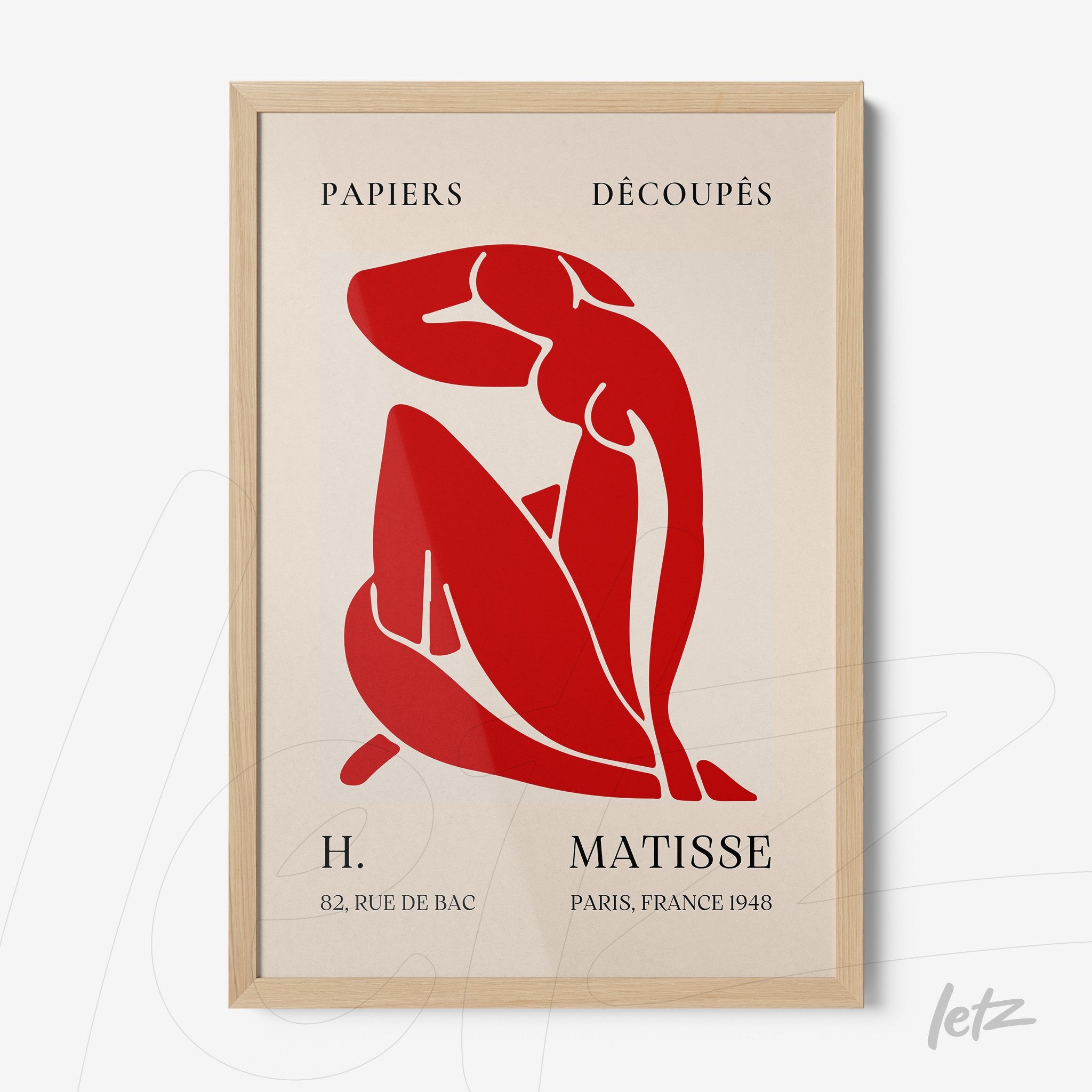 framed art featuring paper cutouts in red and cream colors with light wood frame