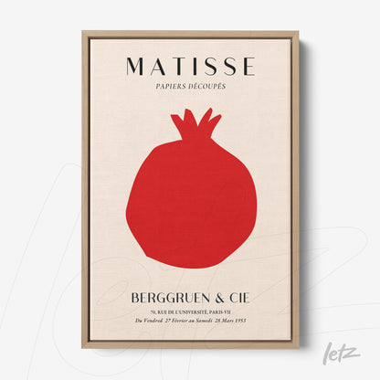 framed modern art piece featuring a pomegranate in red against a light background with a light wood frame
