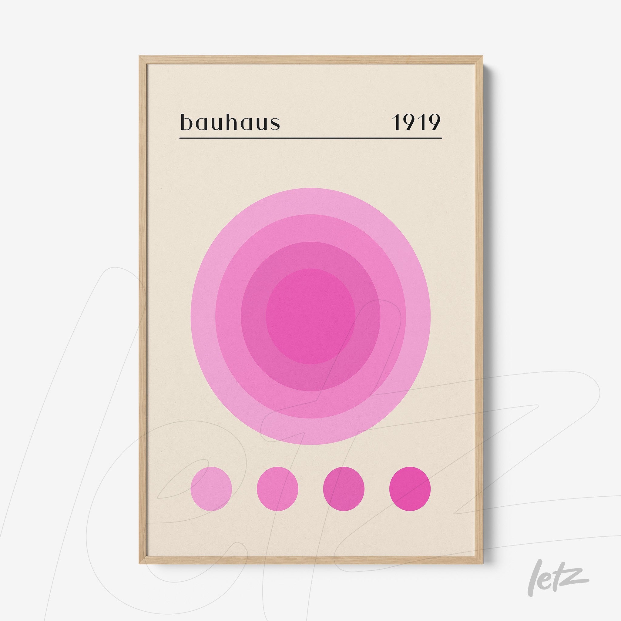 framed art print featuring concentric circles in shades of pink on beige background with text bauhaus 1919 in light wood frame